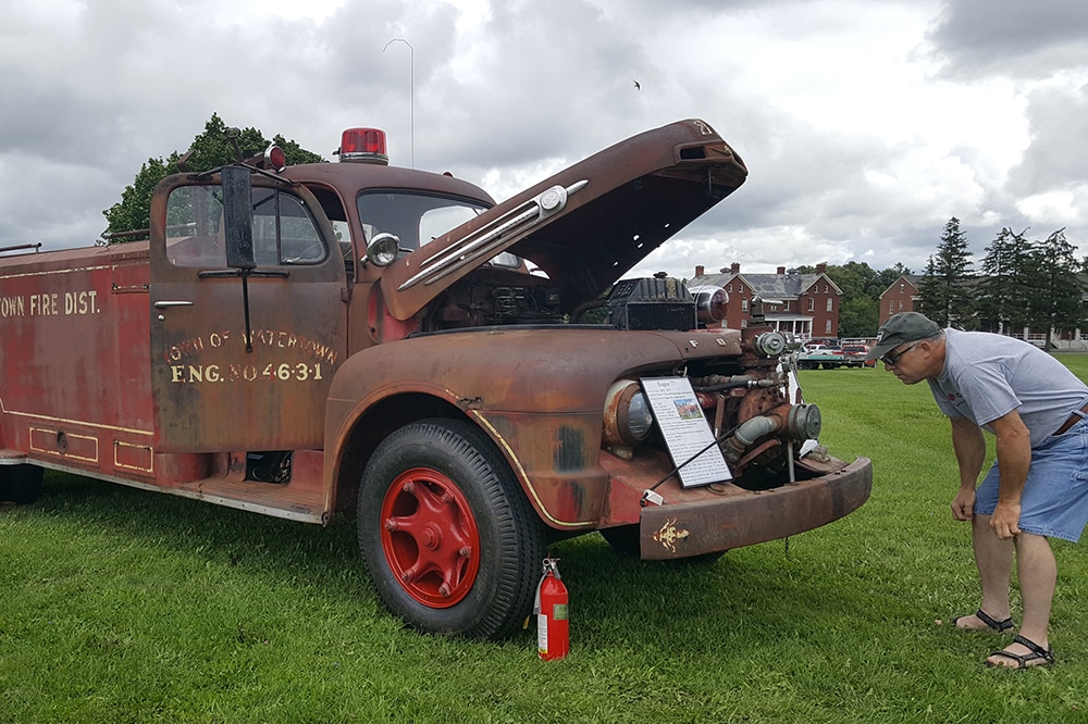 A man looking at the engine of a vintage firetruck