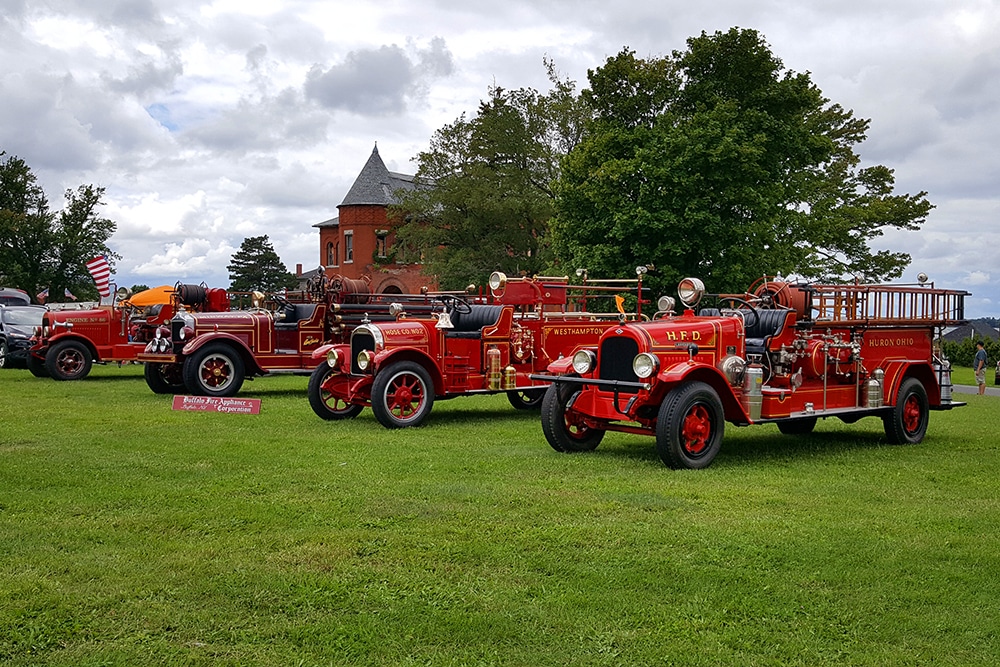 A row of vintage fire engines on a grassy lawn