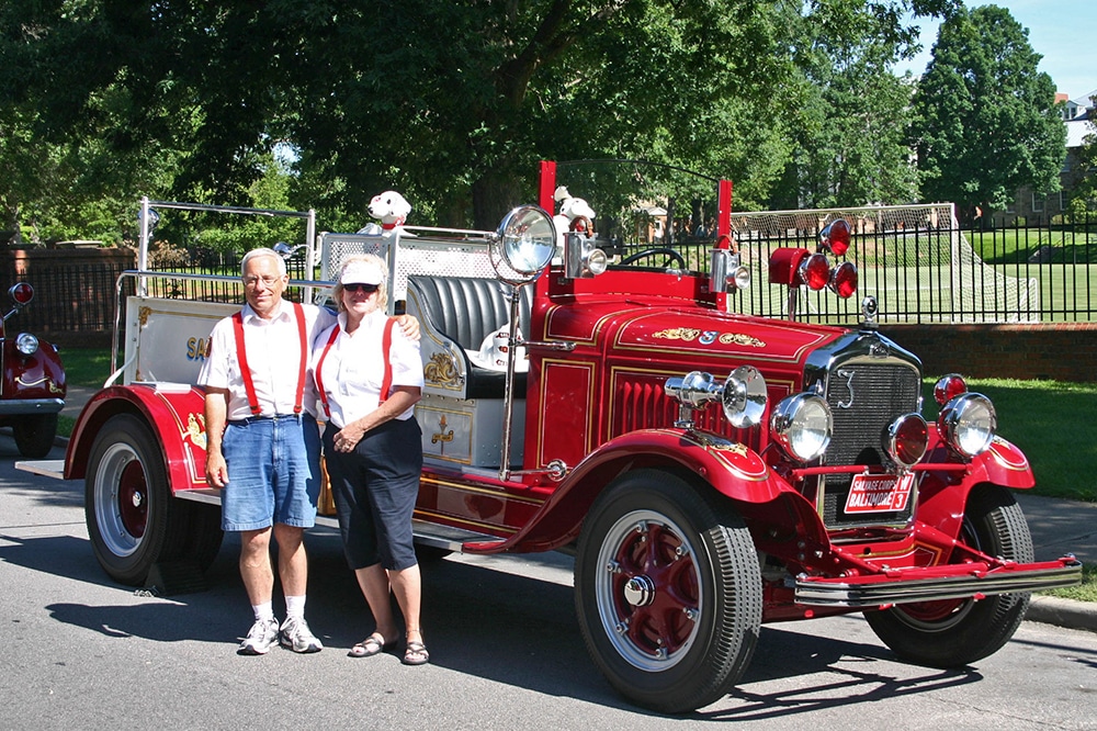 Two people standing next to a vintage fire engine
